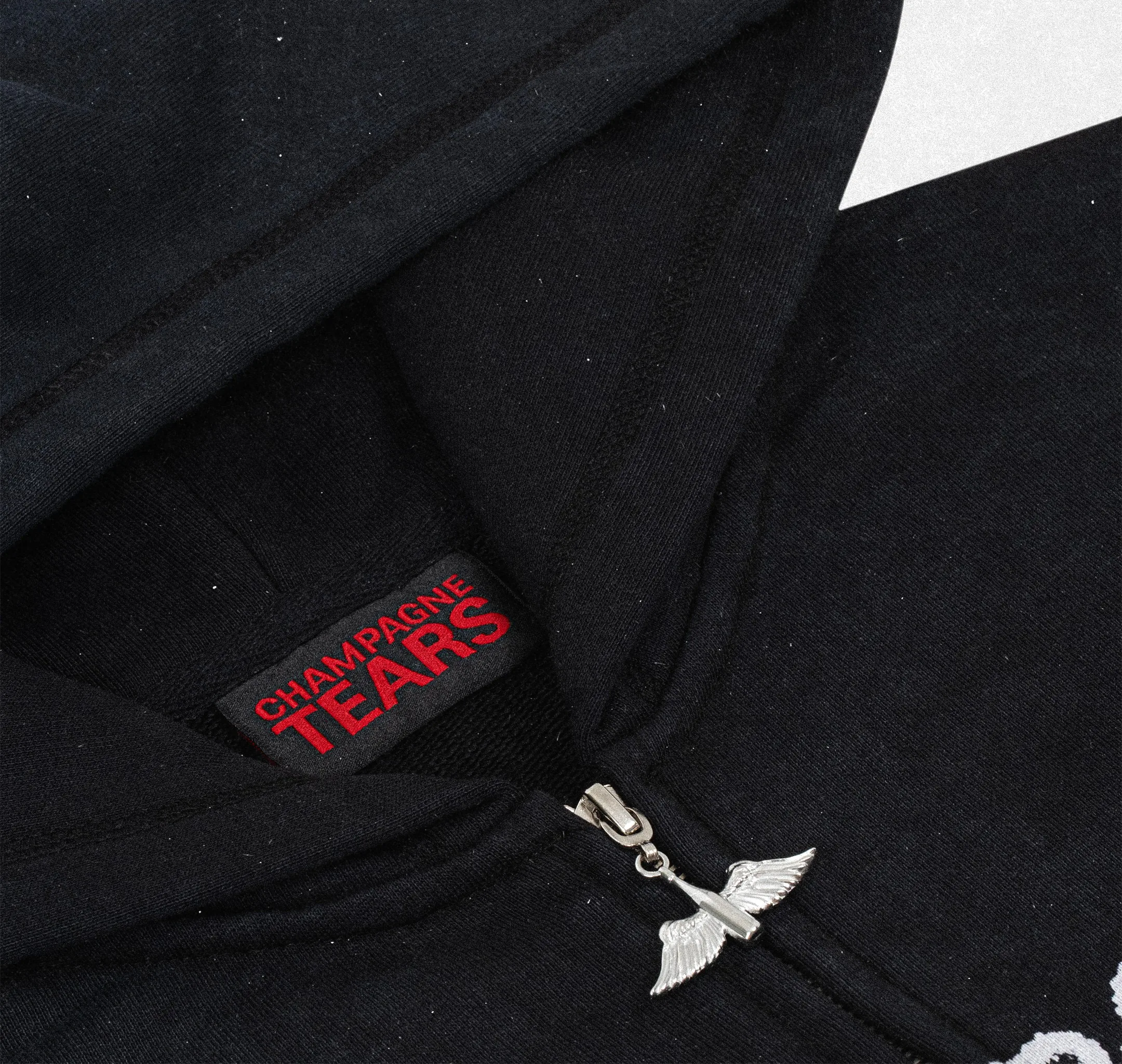 Détail étiquette Champagne Tears sur hoodie noir.