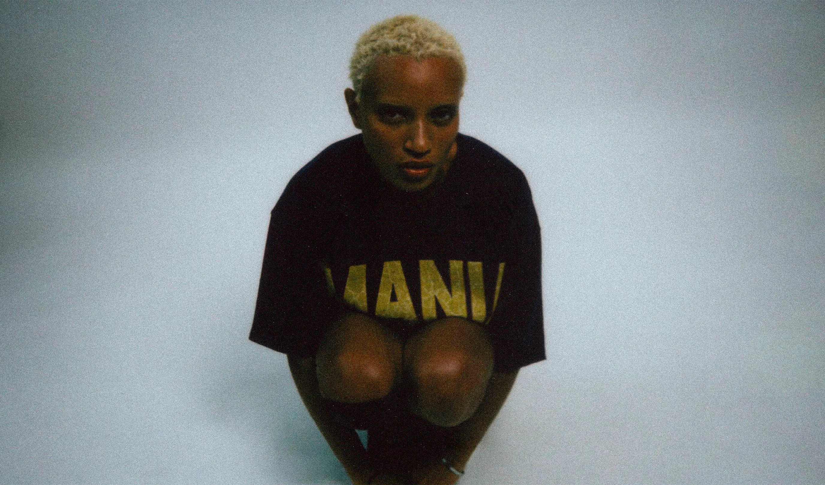 Portrait assis portant un t-shirt Mania noir.